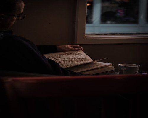 man reading a book in a comfortable chair during a quiet evening